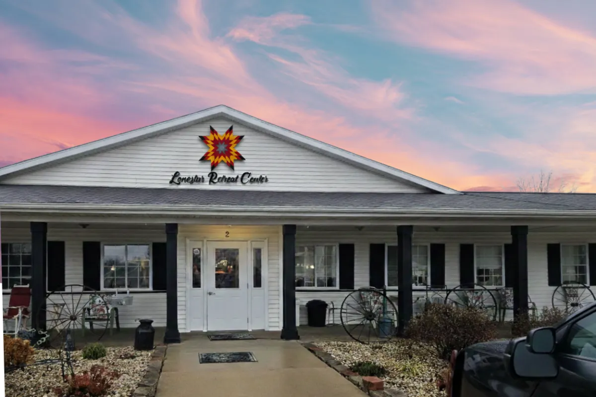 A group of women aged 40-75, gathered around a large wooden table, quilting together in a sunlit room with large windows overlooking a lush green landscape. The women are smiling, focused on their craft, and surrounded by colorful fabrics and sewing tools. The atmosphere is warm, inviting, and creative.
