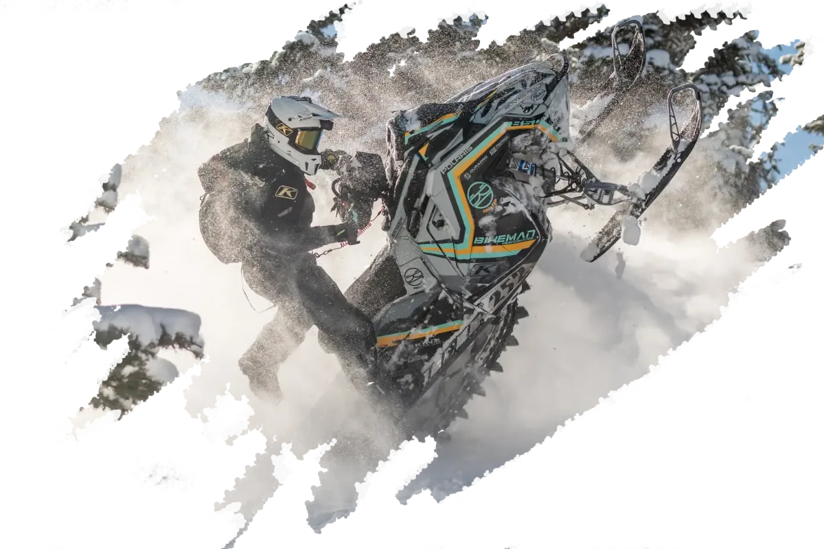 Cole Willford launching off a snow-covered mountain on a snowmobile