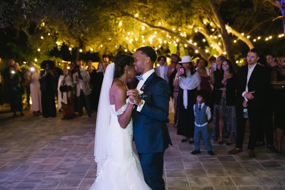 A couple performing a wedding ritual under a floral canopy in a ballroom