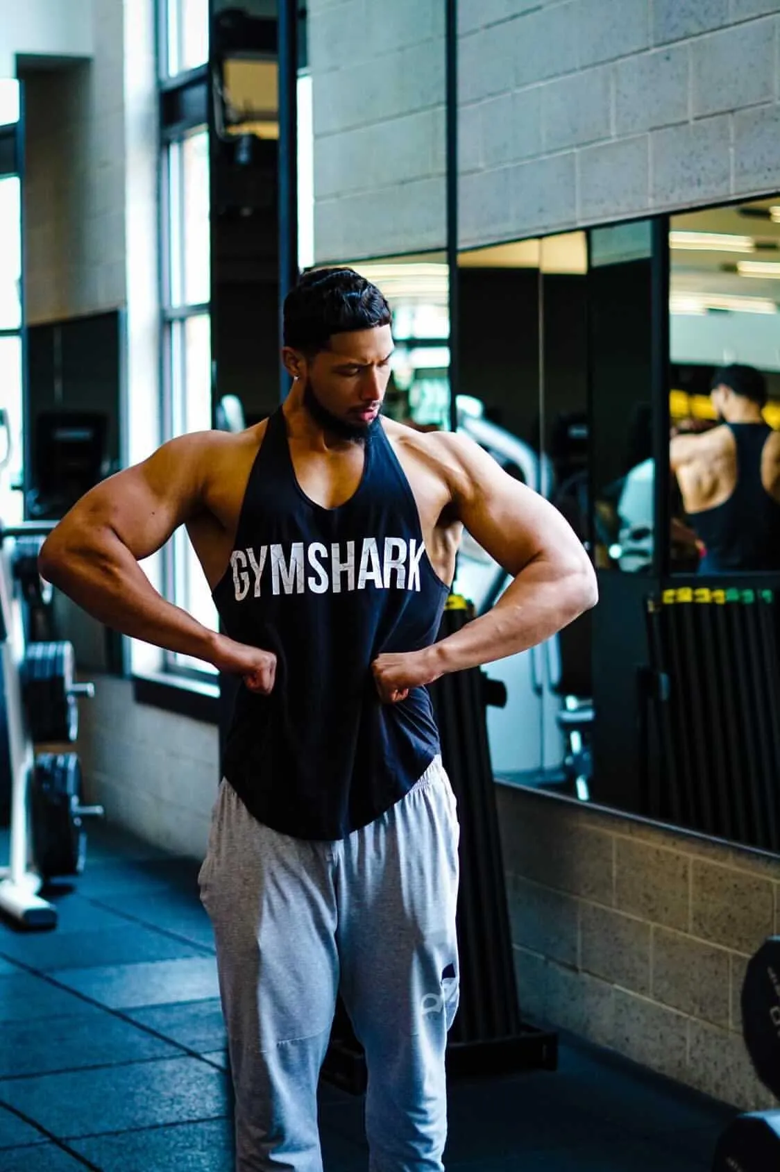 topless man in black shorts carrying black dumbbell