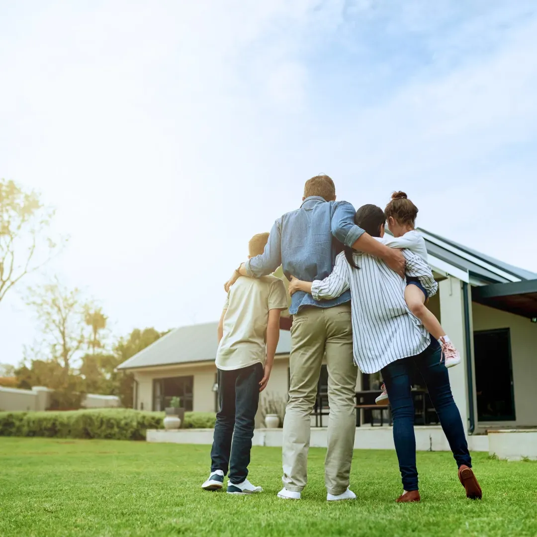 Family hugging in front of new home