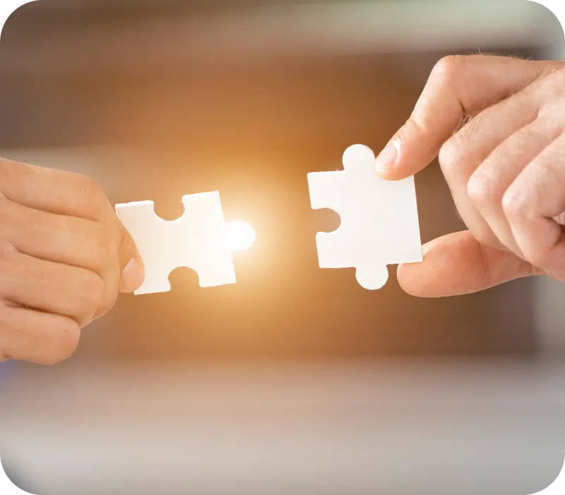 Two hands holding puzzle pieces being joined together