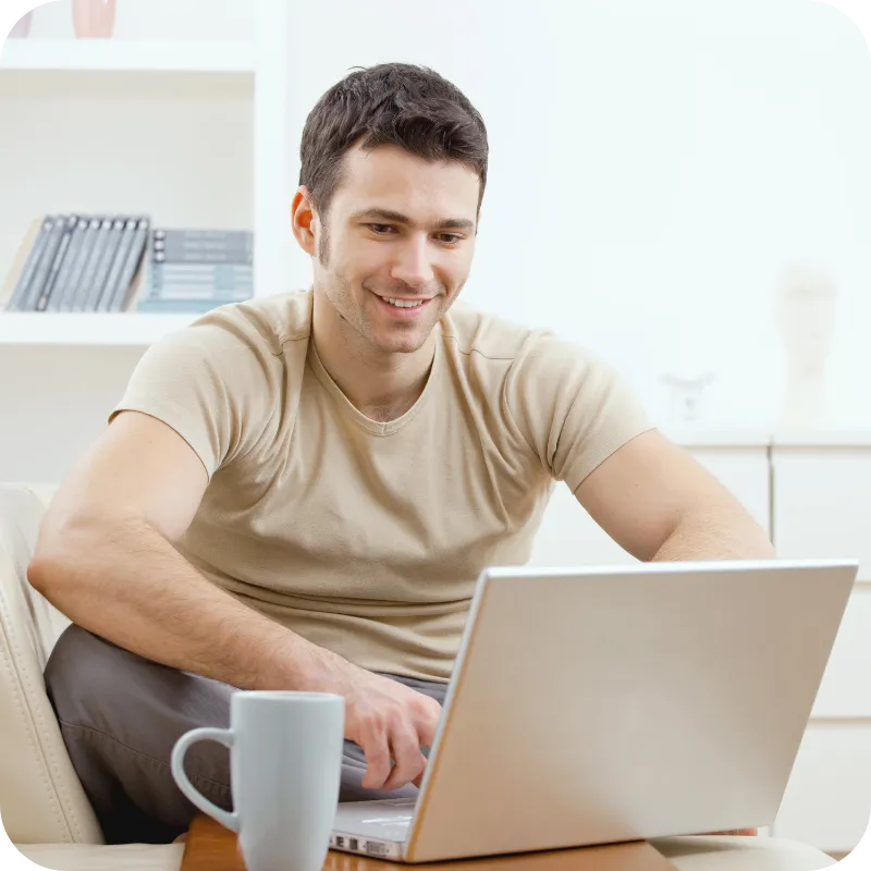Man leaning back at a desk, smiling