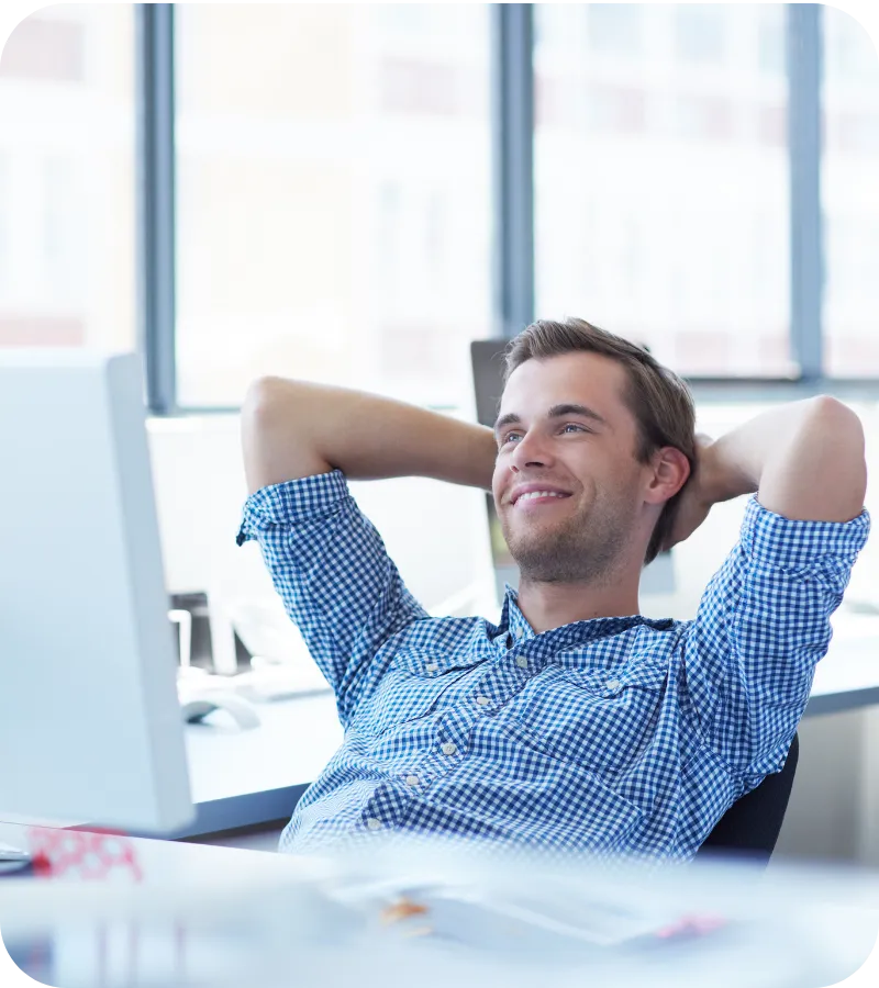 Man leaning back in a chair, smiling at a desk.