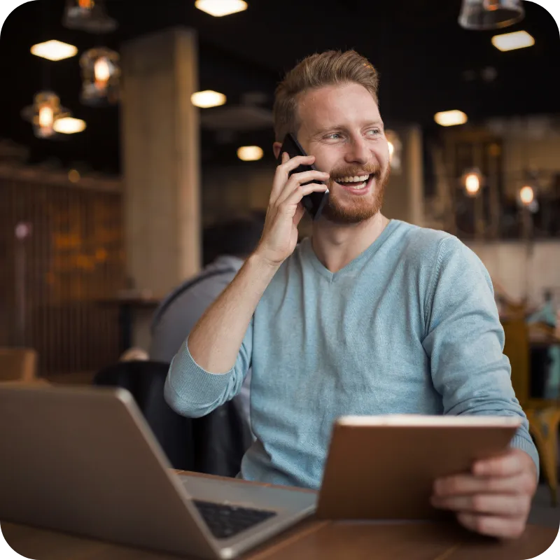 Man talking on a phone while working on a laptop.