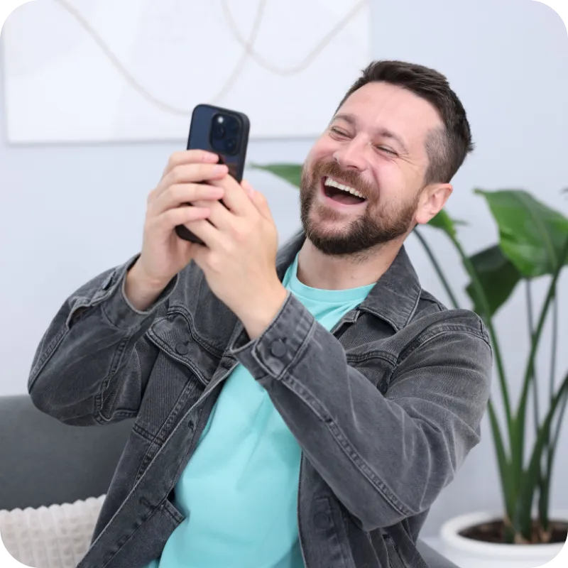 Man smiling while holding a smartphone.