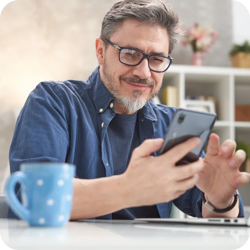 Man using a smartphone while sitting at a desk.