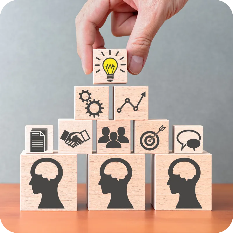 Hand stacking wooden blocks with icons representing shared knowledge