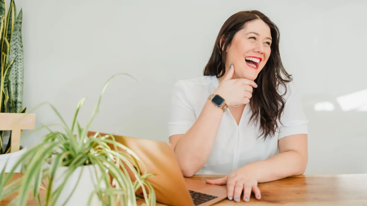 two women sitting at a table looking at a computer screen