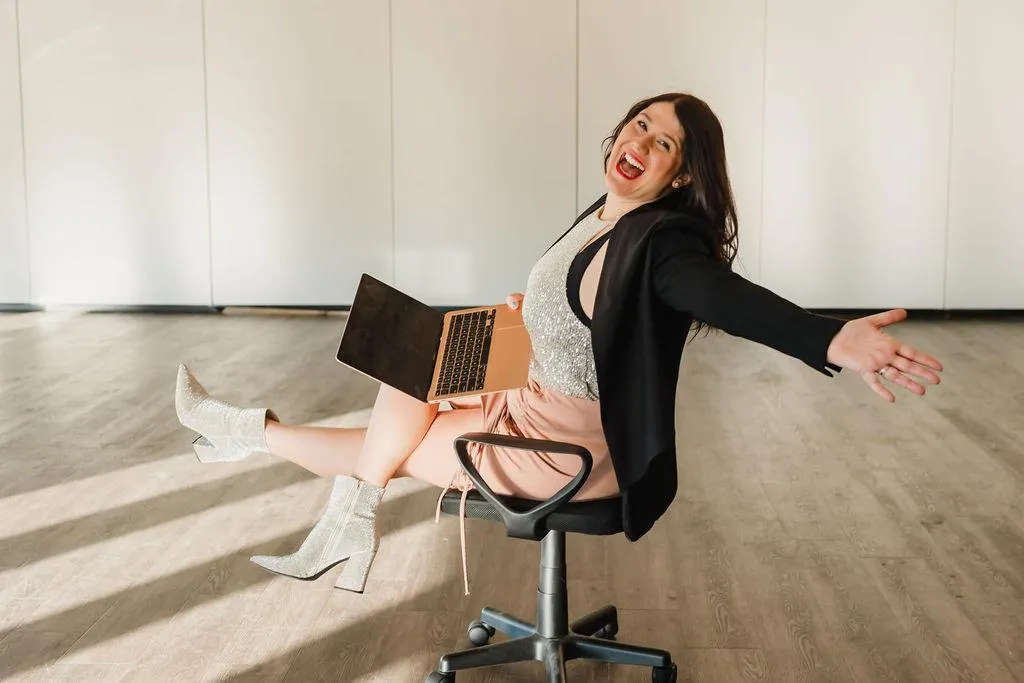 four people all on laptops, two men and two women, listen to person talking in a board meeting