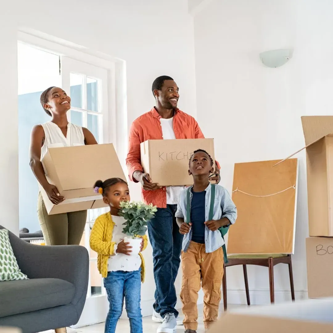 A happy family holding cardboard boxes, stepping into a clean home, showcasing move in and move out cleaning services by Maryland Spotless Maid Service.