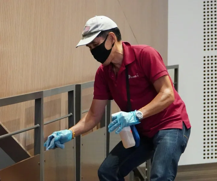 A professional background-checked technician from Maryland Spotless Maid Service wearing a protective mask and gloves while detailing and sanitizing surfaces in Frederick, MD.