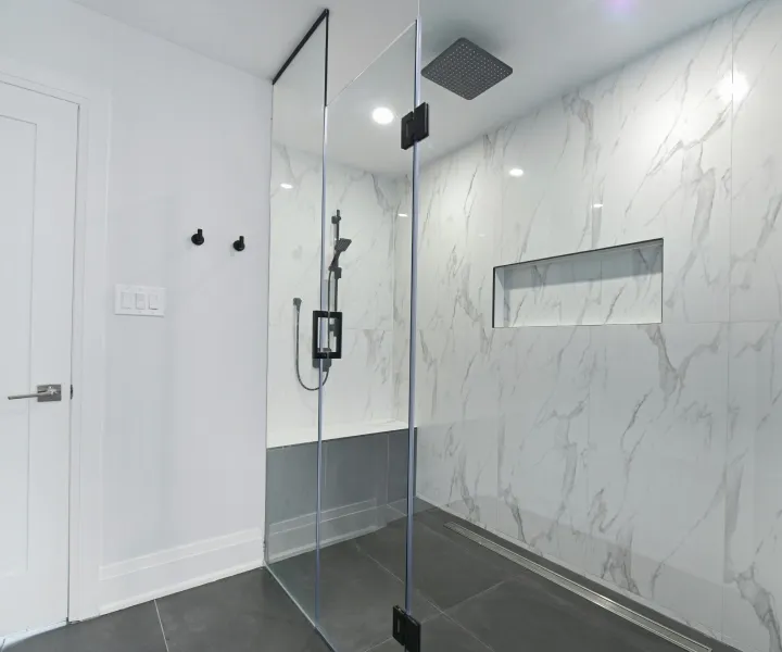 Immaculate modern glass shower and marble-style tiled bathroom thoroughly sanitized and detailed by Maryland Spotless Maid Service technicians in Frederick, MD.
