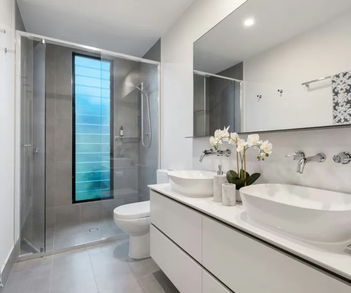 Spotless modern bathroom featuring a glass shower enclosure and double vanity thoroughly sanitized by Maryland Spotless Maid Service cleaners in Rockville, MD.