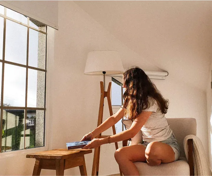 A Rockville homeowner relaxing with a book in a sunlit, freshly dusted living room after a professional maid service visit by Maryland Spotless Maid Service.