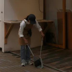 Professional cleaner sweeping floor debris into a dustpan, representing customizable hourly house cleaning services in Maryland