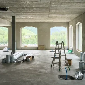 Spacious residential room under renovation with drywall dust and ladders, prepared for post-construction cleaning services by Maryland Spotless Maid Service