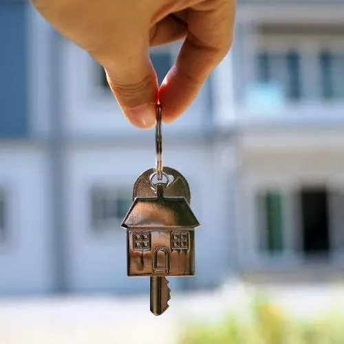 holding keys in front of their new house