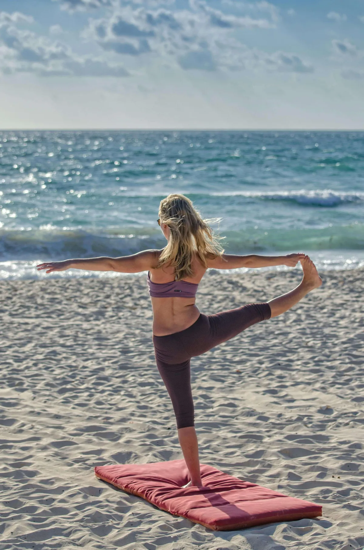 Vrouw beoefent yoga op het strand als voorbeeld van lichaamsbeweging met focus op balans en coördinatie