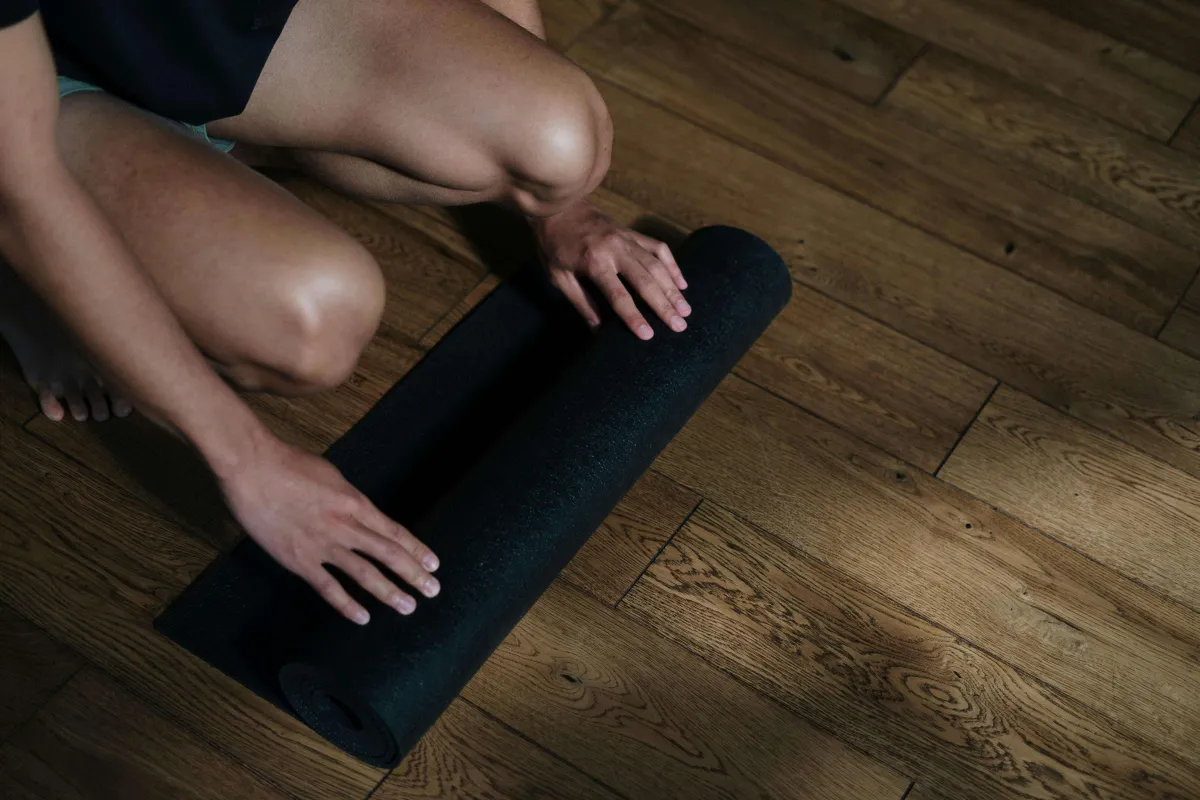 Persoon die een yogamat uitrolt als onderdeel van een ochtendroutine vol discipline en motivatie
