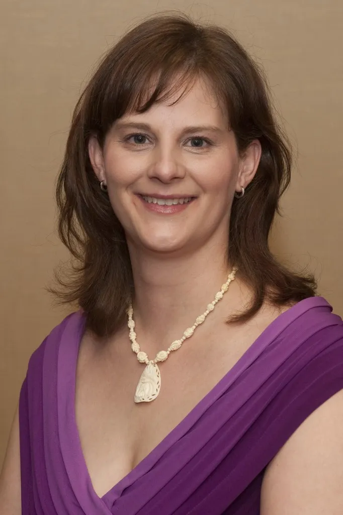 Portrait photo of a smiling woman wearing a purple dress.