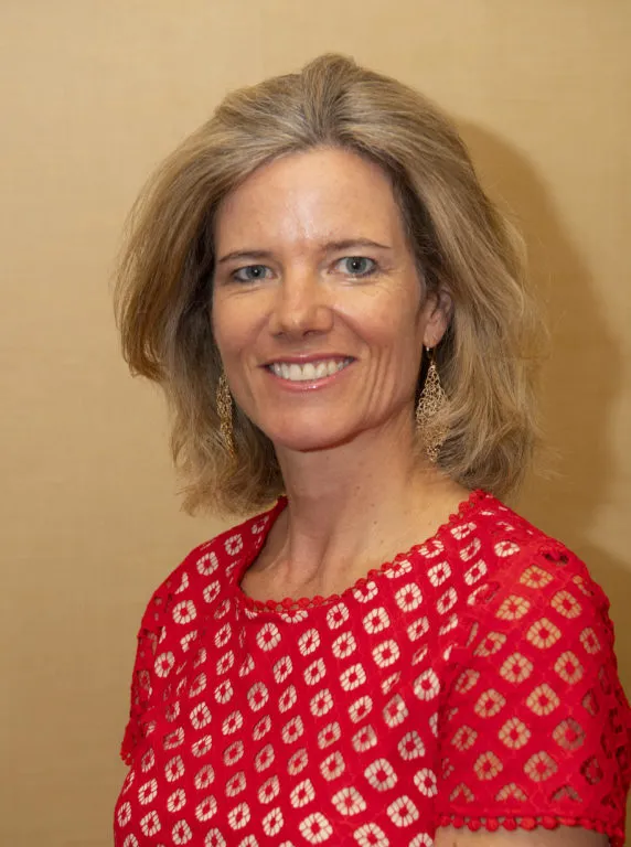 Portrait photo of a smiling woman with blonde hair wearing a patterned red and white top.