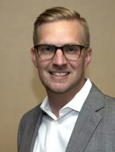 Portrait photo of a man wearing glasses and a suit.