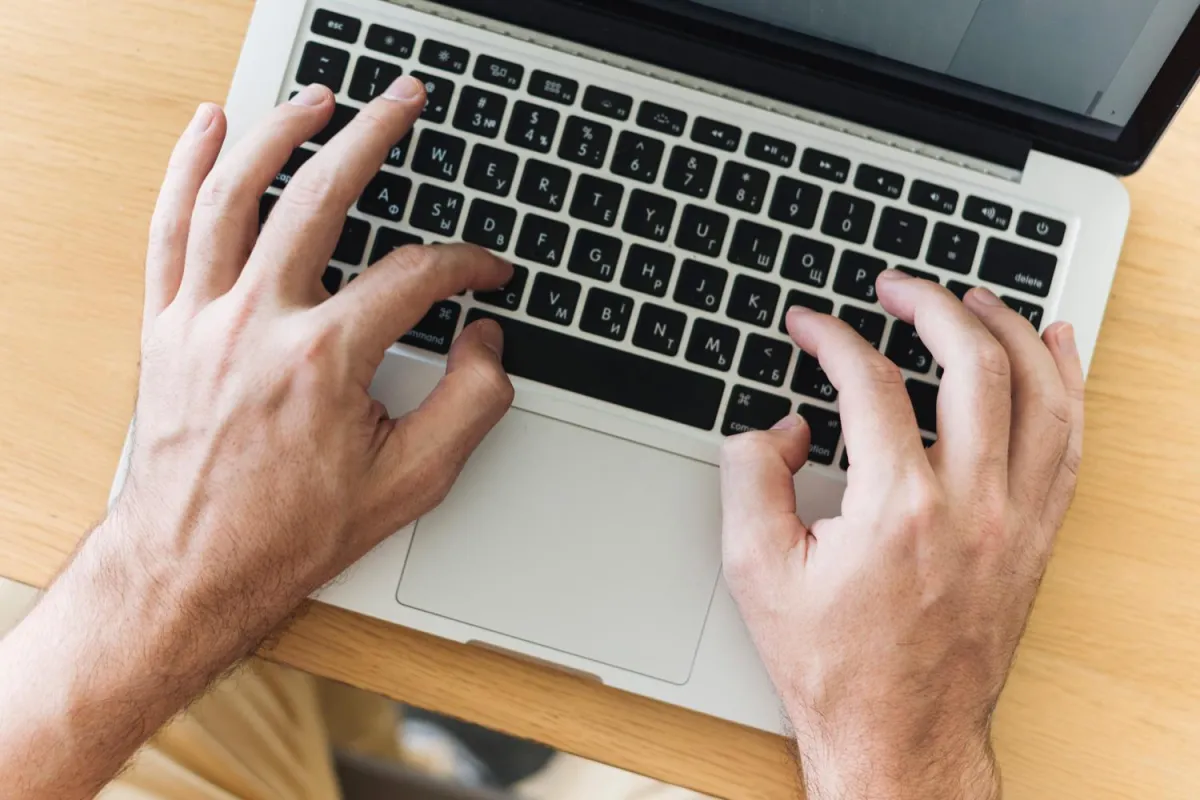 Close up of man's hands typing on laptop