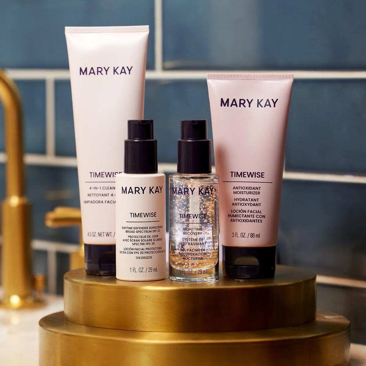 Mary Kay TImewise set, four pink bottles with black tops. They are sitting on a gold stand in a black and white bathroom.