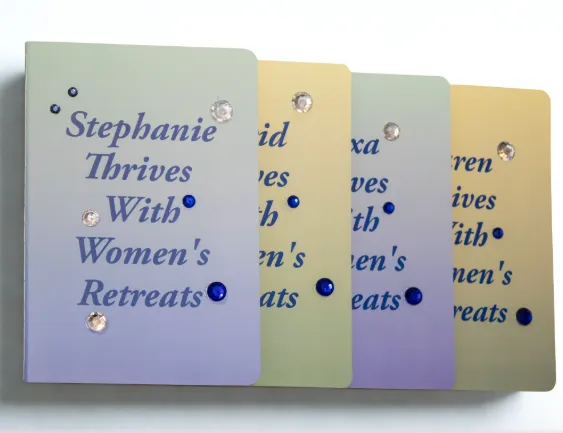 Four personalized journals in different colors (silver, gold, blue, green) lying side by side