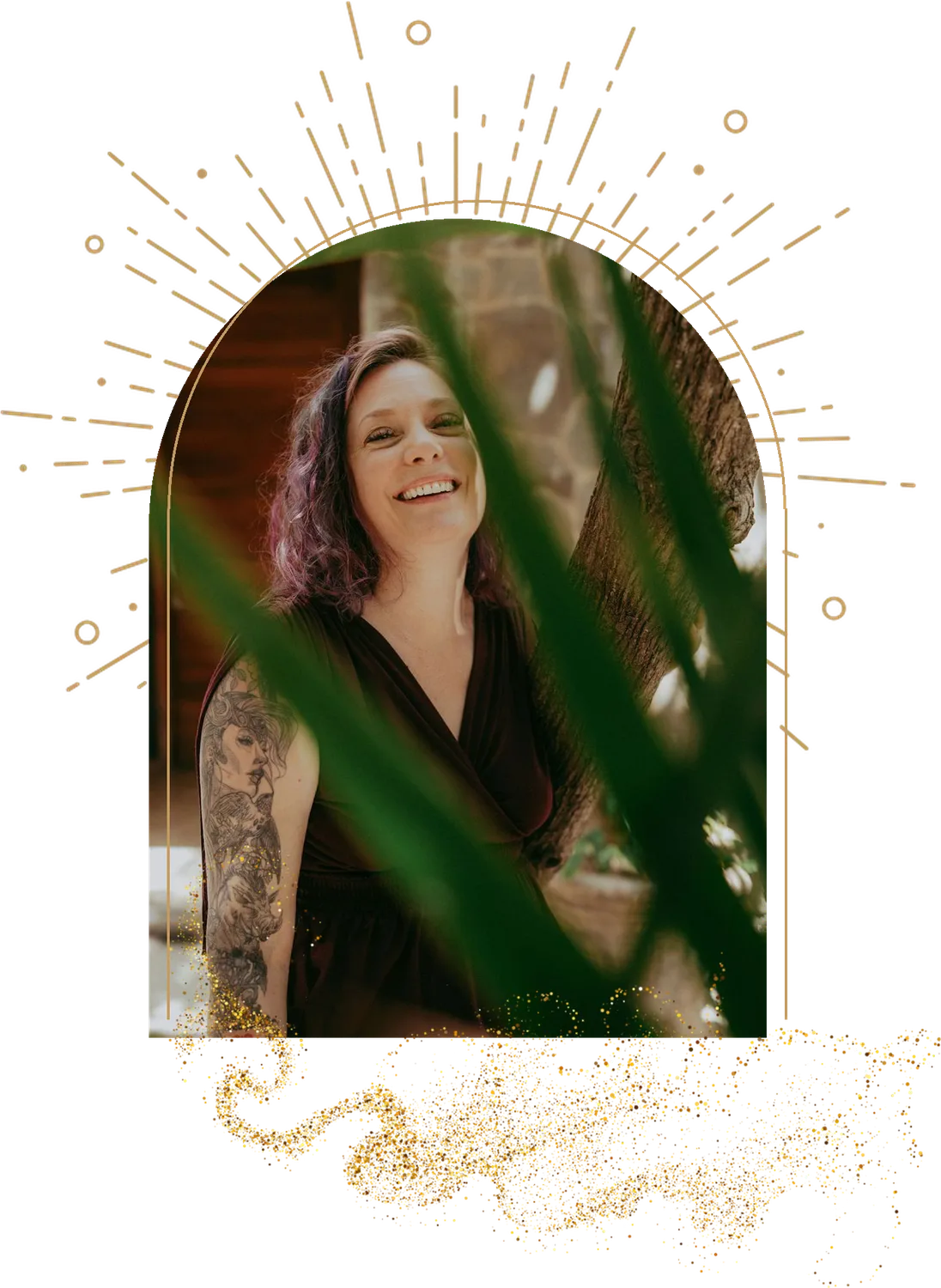 Annie smiling through palm leaves in a deep red dress