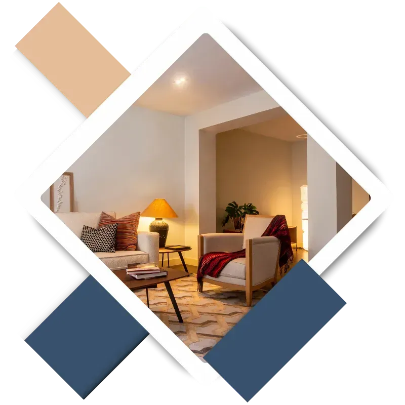 Cozy living room featuring two armchairs, a coffee table with books, decorative pillows, a stylish lamp, and a plant, showcasing a welcoming atmosphere ideal for interior painting services in The Woodlands, TX.
