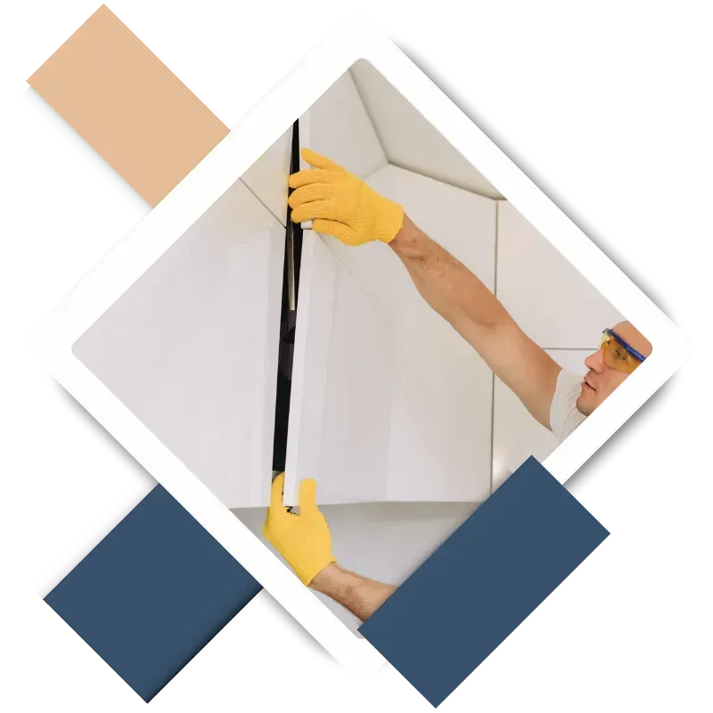 Man wearing yellow gloves and safety glasses measuring a wall during home repair, illustrating professional handyman services in Kingwood, TX.