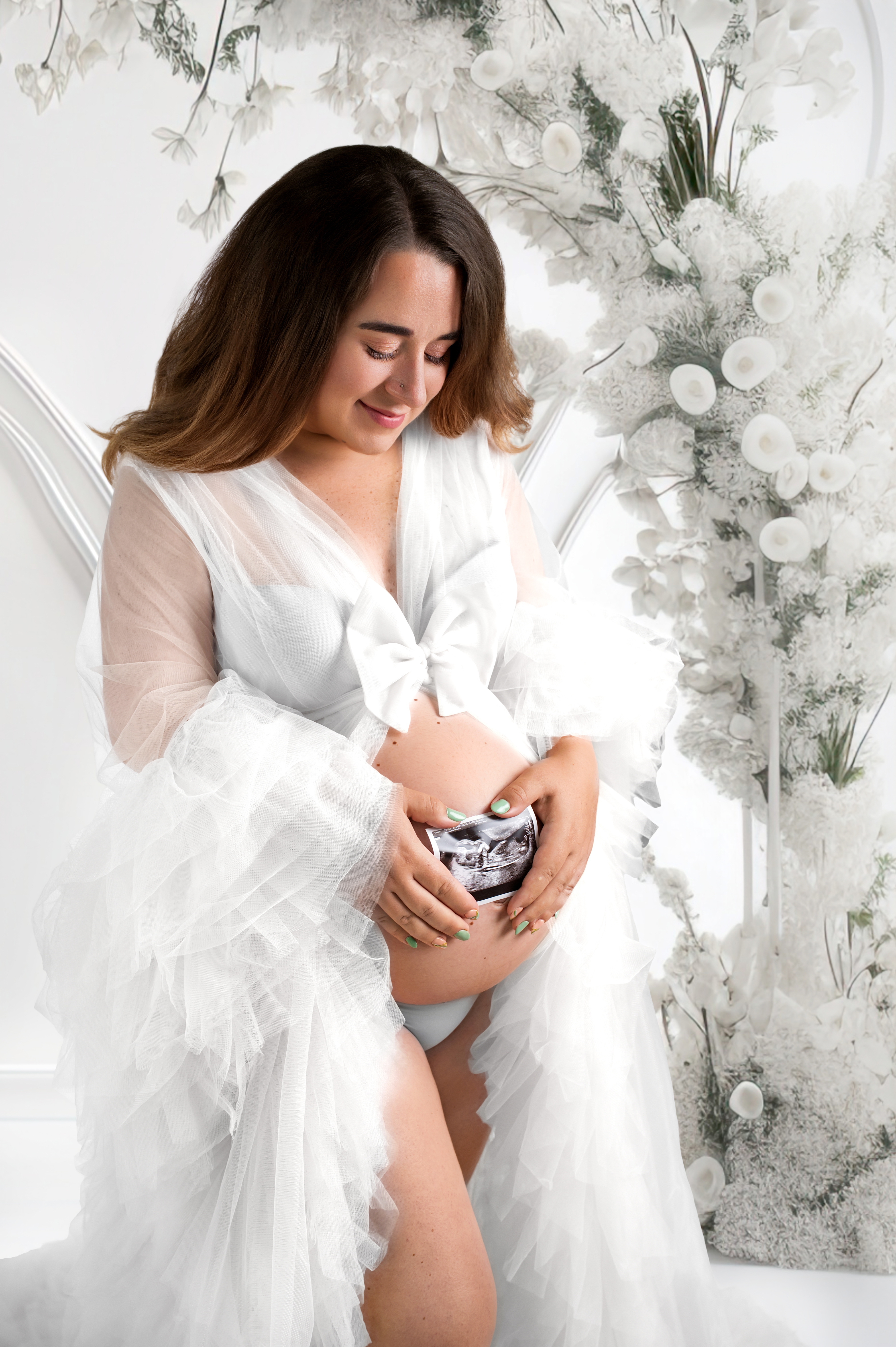 A warm, sunlit studio portrait of an expectant mother in a flowing gown, celebrating the anticipation of maternity.