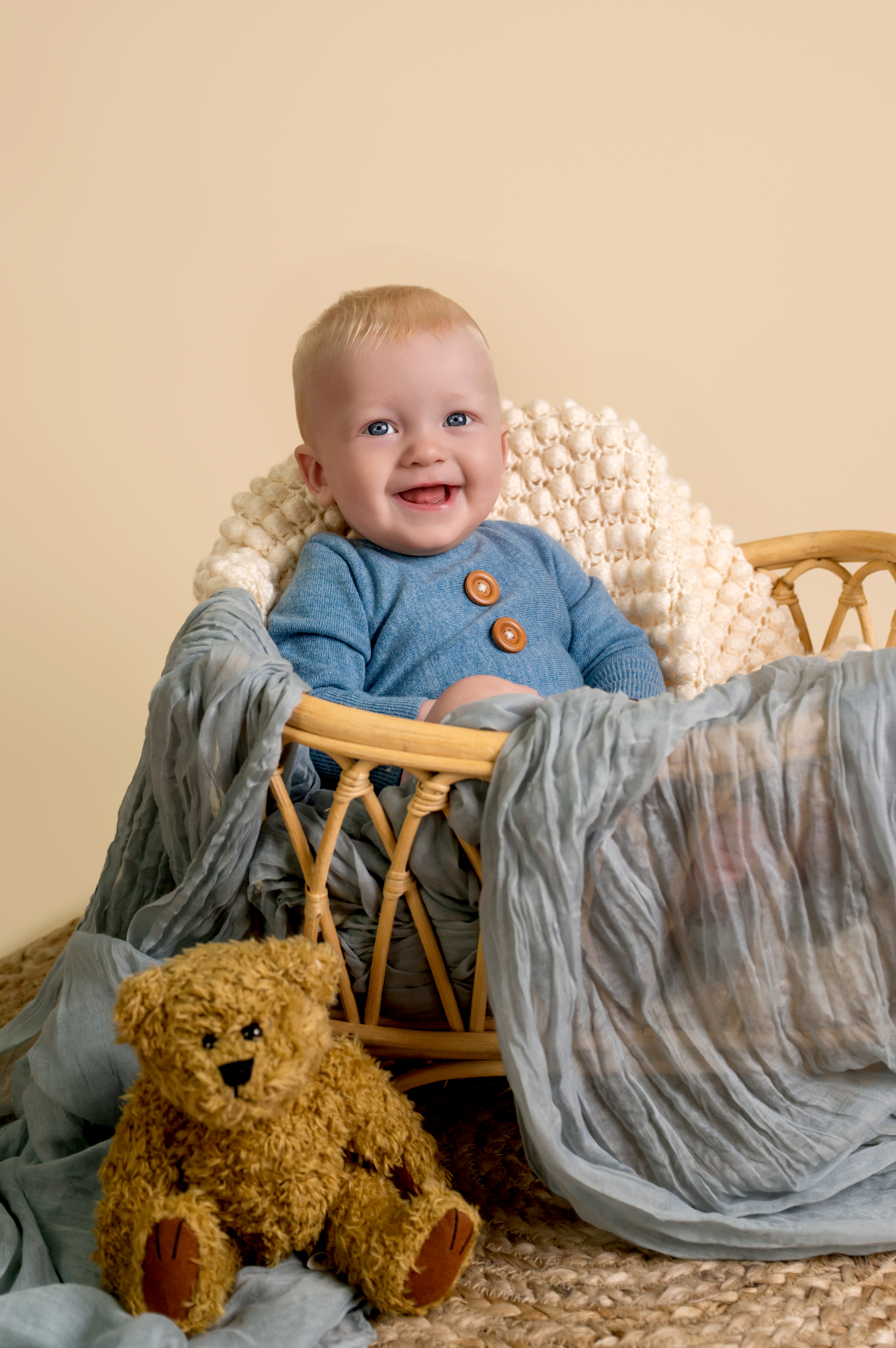 A six-month old baby sitting up with a joyful expression, captured in soft natural light.