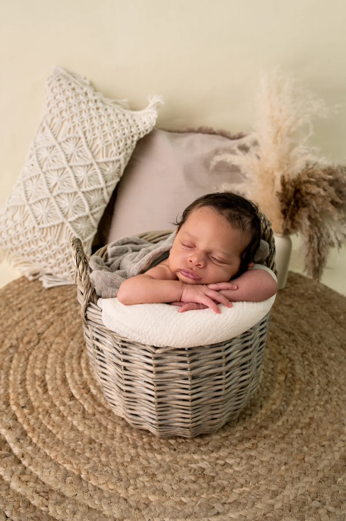 Soft-focus artistic portrait of a sleeping newborn curled in organic textured neutral wraps