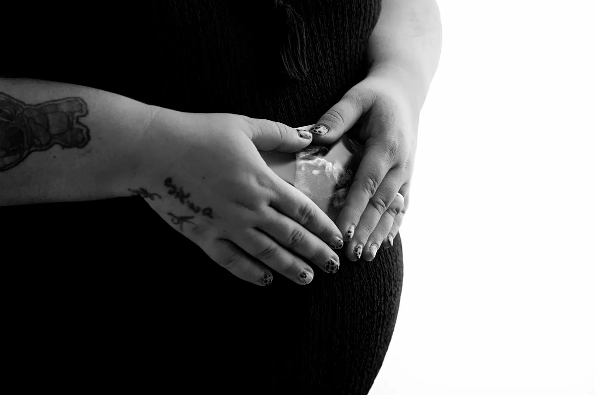 Customer portrait of Grace embracing her baby bump