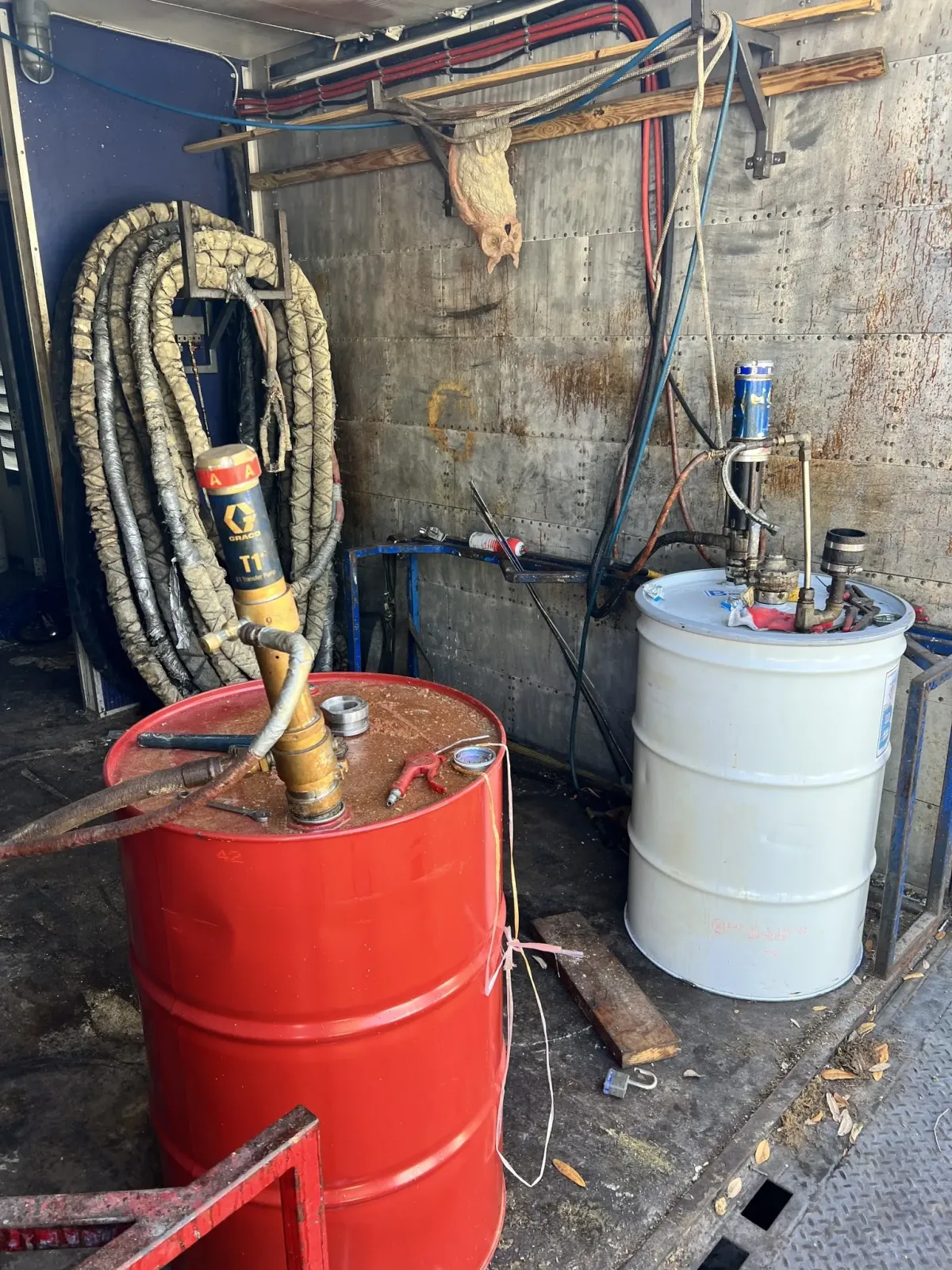 Used spray foam rig interior with red and white chemical drums and hose setup by Spray Tech Services in Panama City, FL