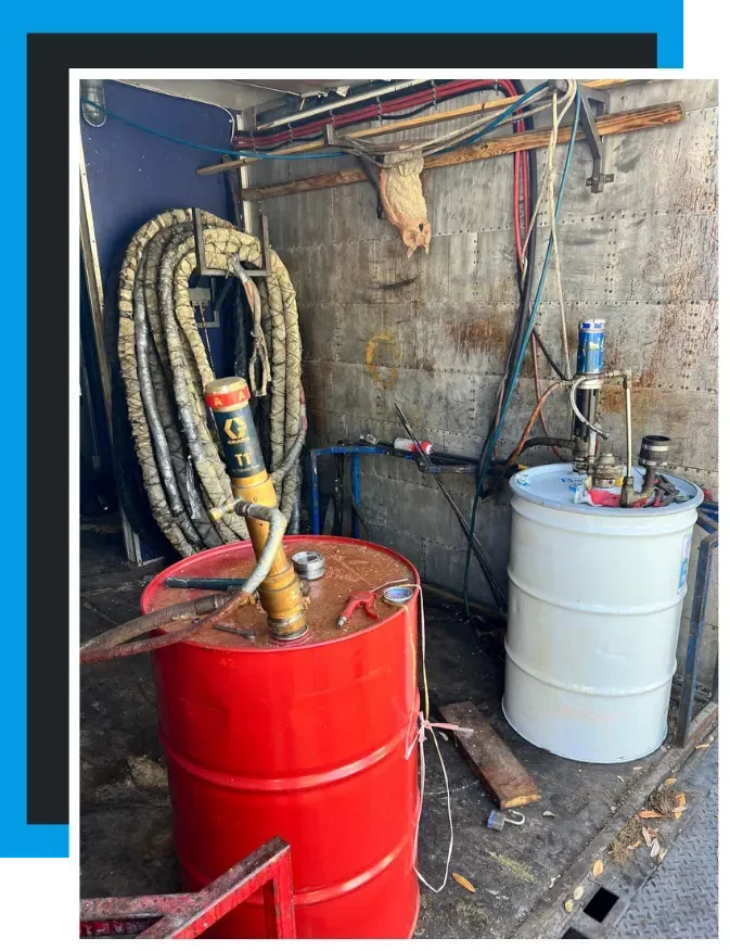 Used spray foam rig interior with red and white chemical drums and hose setup by Spray Tech Services in Panama City, FL
