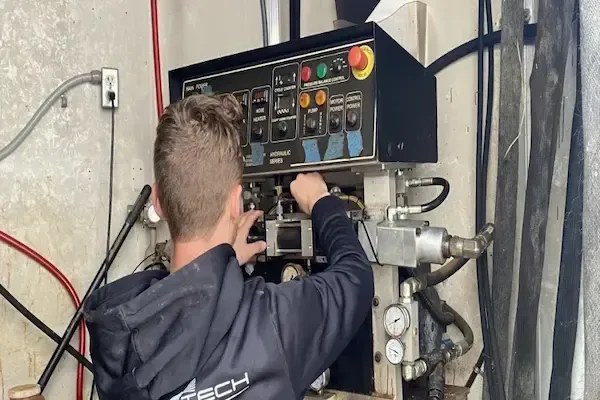 Spray Tech Services technician repairing spray foam machine inside custom rig