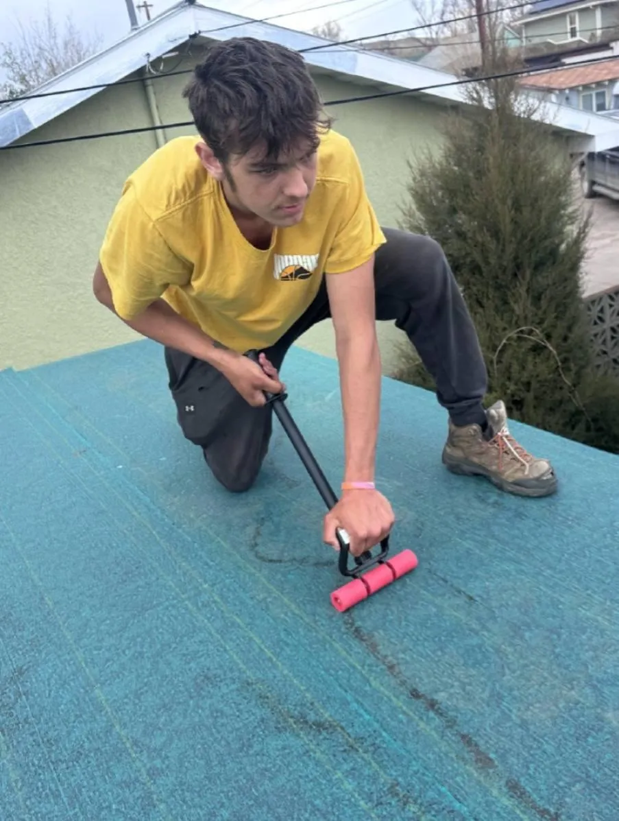 Blue metal roof on rural ranch outbuilding with standing seams and Montana hills in the background.
