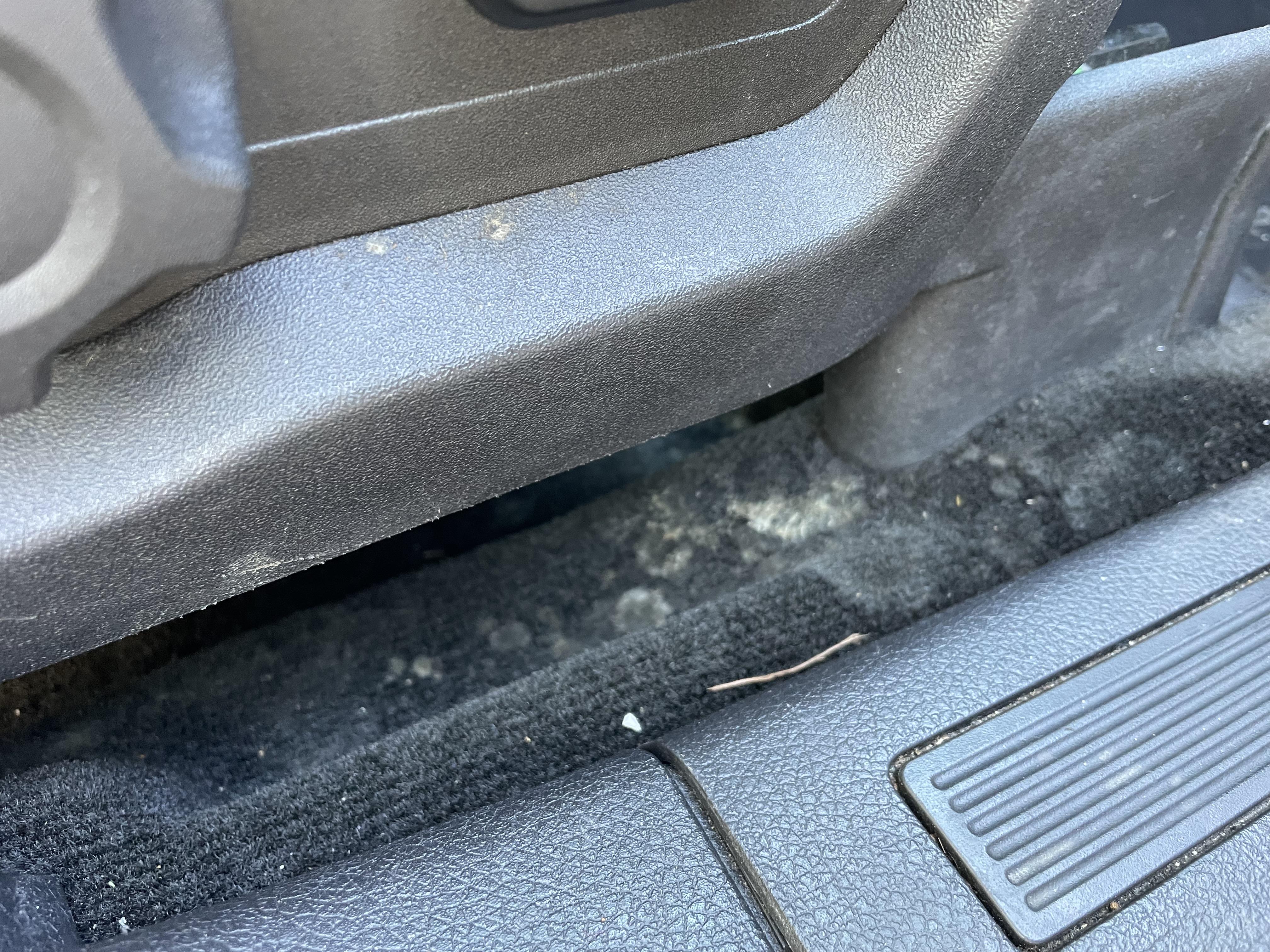 Dirt and mold trapped beneath a vehicle seat contributing to lingering interior odors