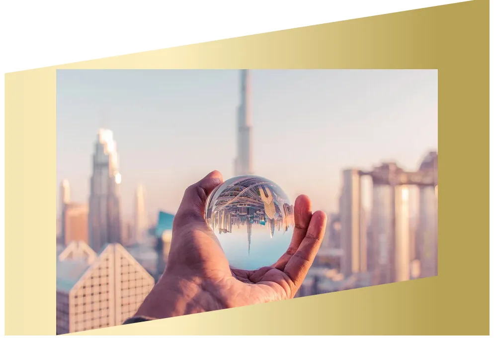 Hand mit Kristallkugel Eine Hand hält eine durchsichtige Glaskugel, in der sich eine moderne Stadtlandschaft spiegelverkehrt abbildet. Der Hintergrund zeigt Hochhäuser im Sonnenlicht. Goldfarbiger Rahmen