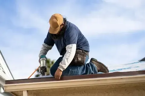 Roofer nailing asphalt shingles along roof edge during installation by Maple Grove Roofing Co.