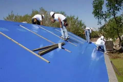 Crew securing blue emergency tarp over storm-damaged residential roof in Maple Grove by Maple Grove Roofing Co.