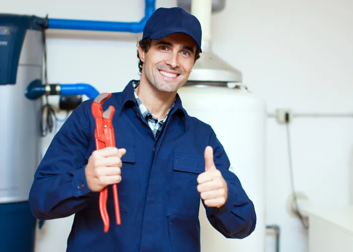 A gumball machine stands next to an electrical outlet.