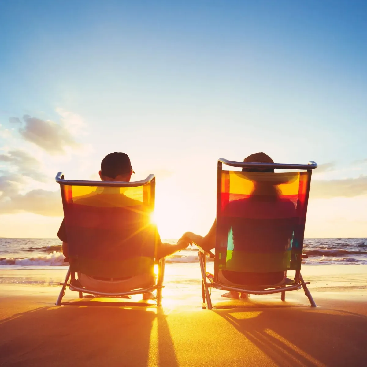 A couple sitting on a beach watching the sunset