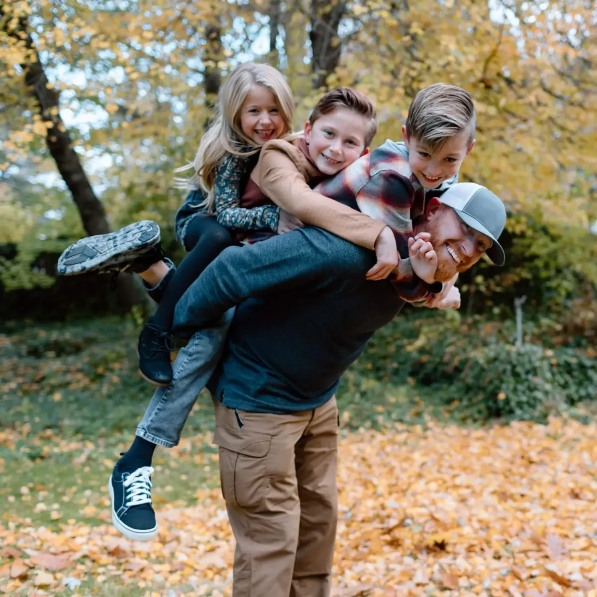 A dad with three kids on his back all smiling