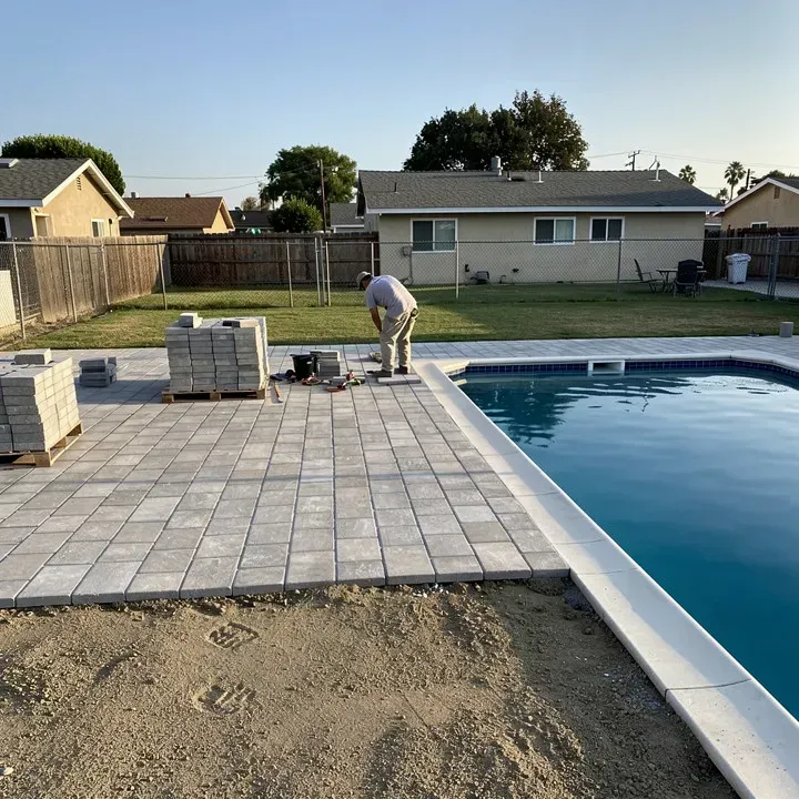 Paver pool deck installation in progress around a backyard pool in Kendale Lakes, Florida