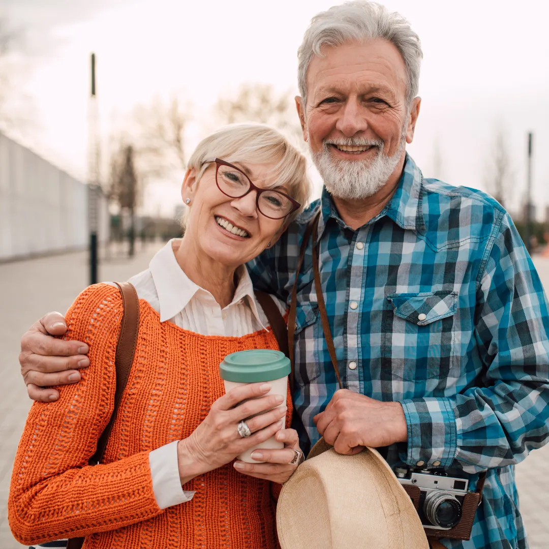 Smiling married couple standing next to each other holding beverage cup